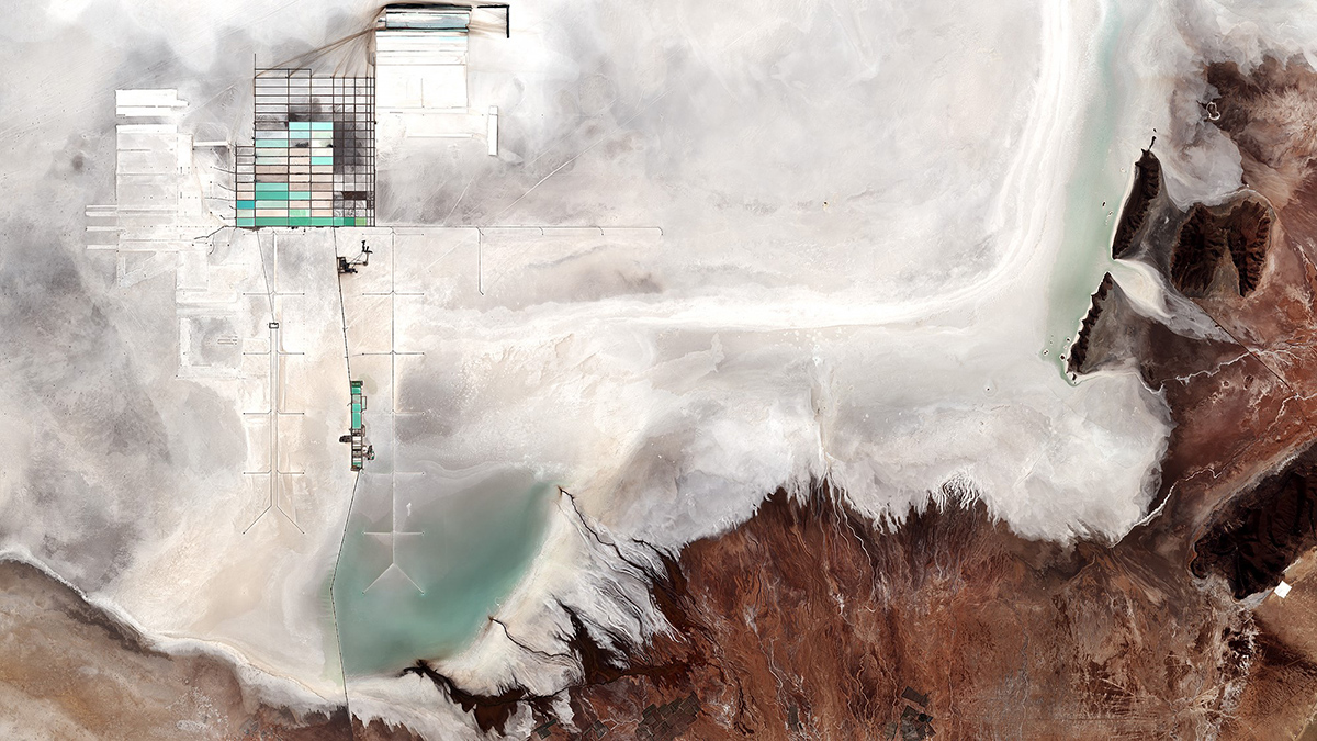 Satellite view of rectangular evaporation ponds used for lithium mining located amid a bright white salt flat.