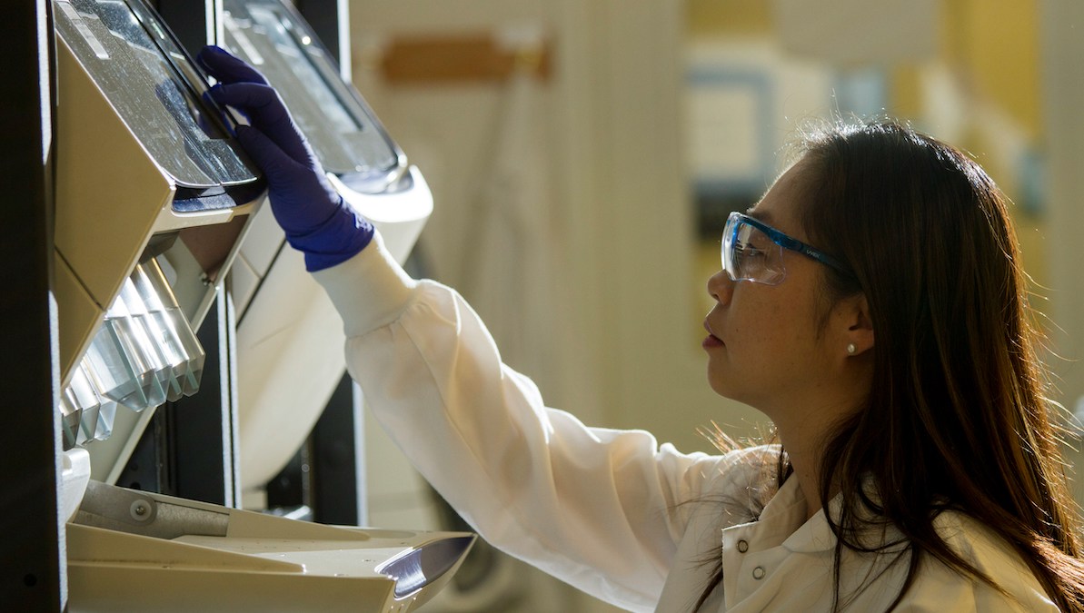 A woman works with a machine in a research laboratory.