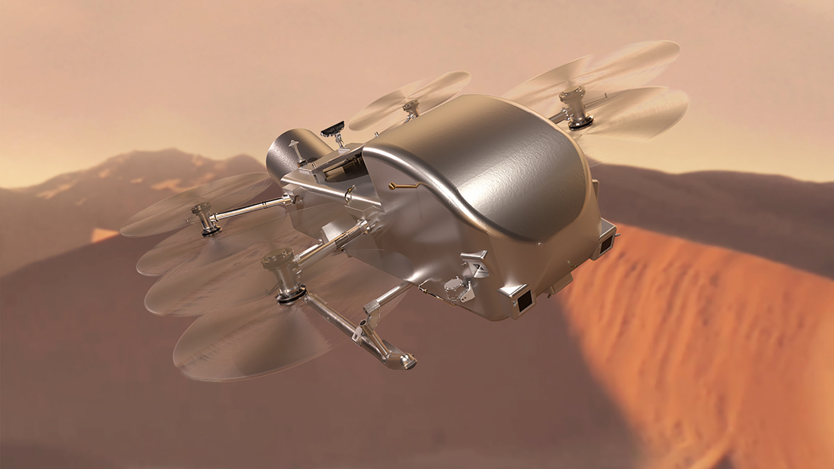 A shiny vehicle with sled skids and four pairs of helicopter-like blades flies over reddish sand dunes.