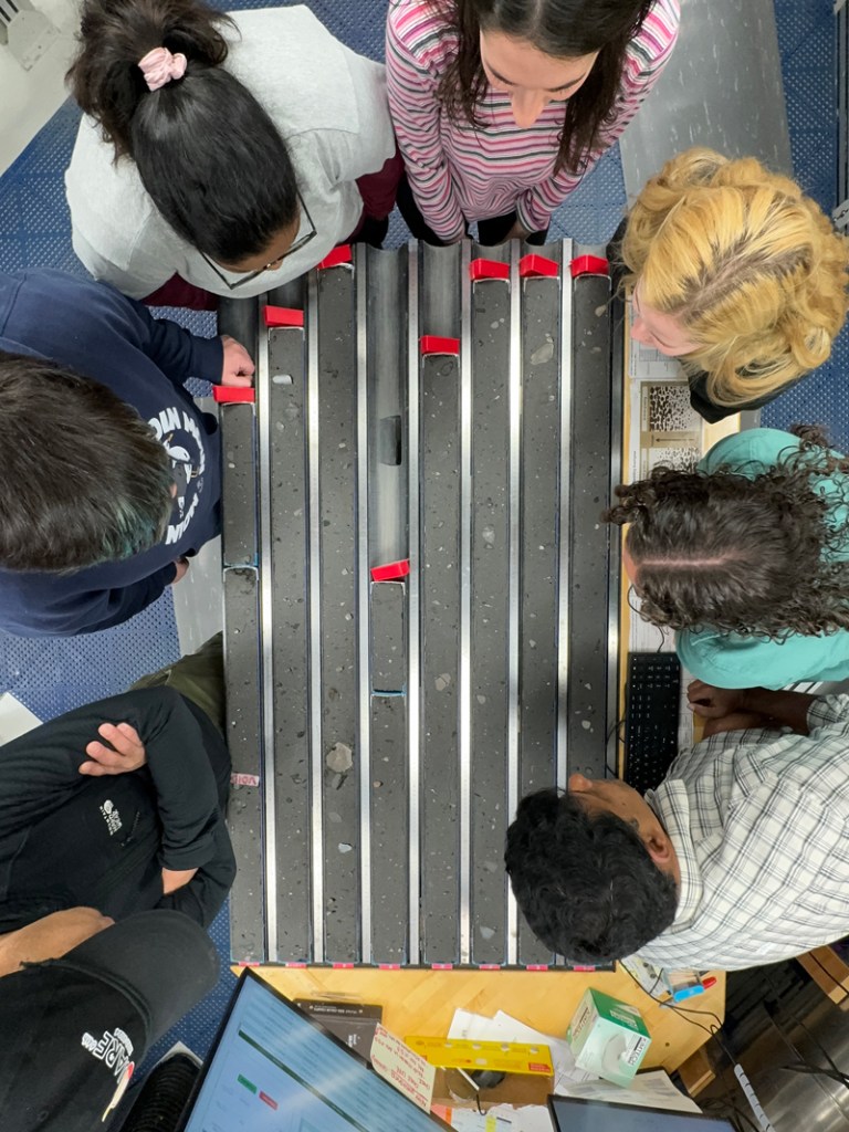 Aerial image of scientists huddled around series of sediment cores on a table