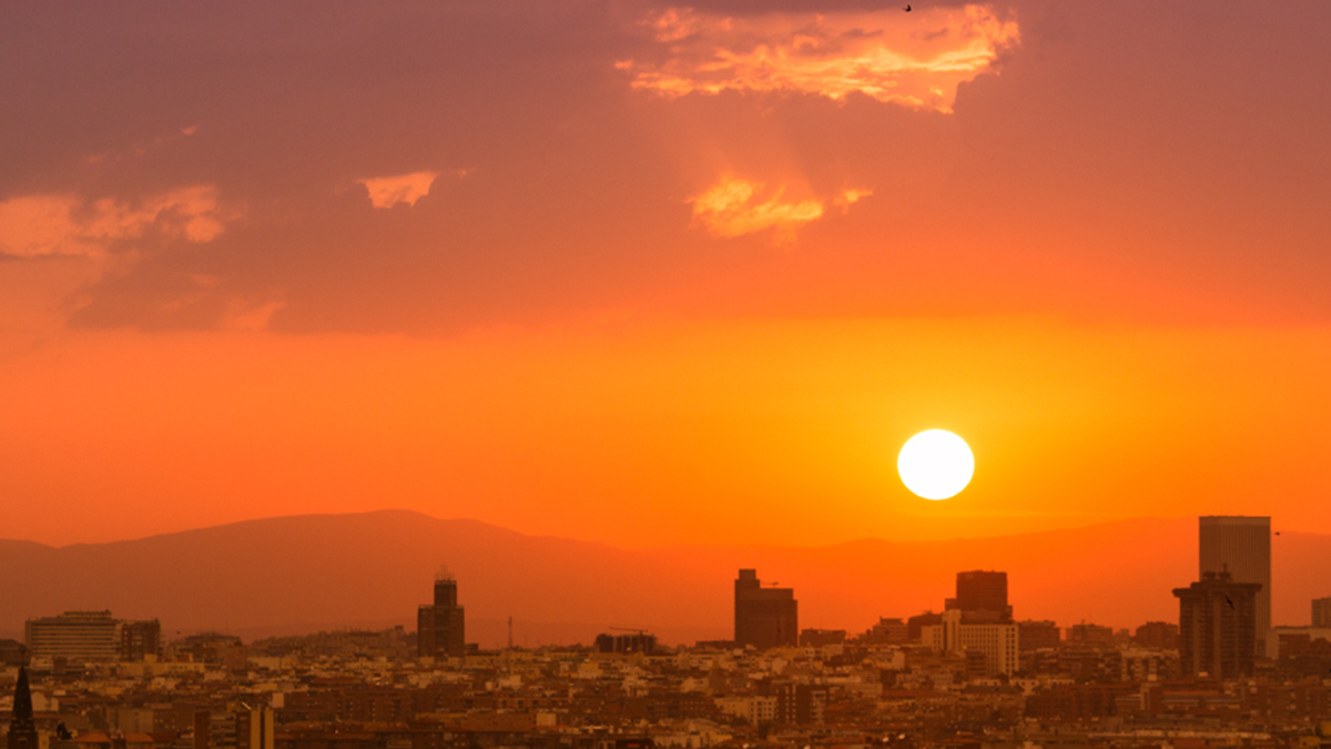 The Sun sets in an orange sky over the city of Madrid.