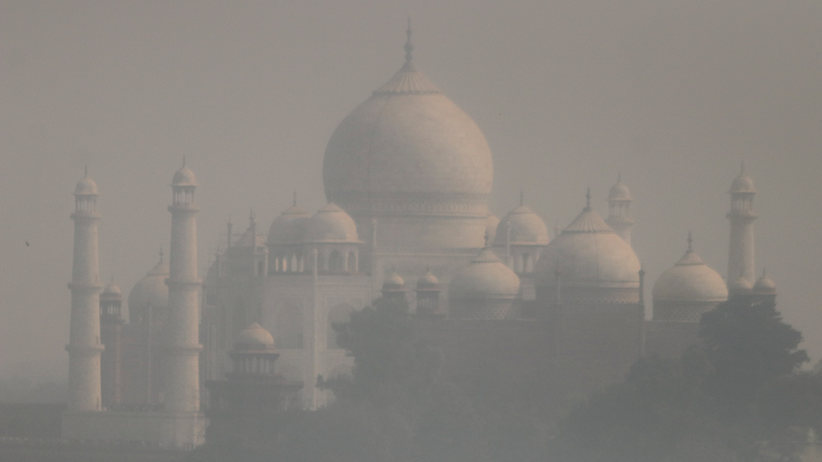 The Taj Mahal is cloaked in a haze of pollution, making the edges of buildings and vegetation blurry.